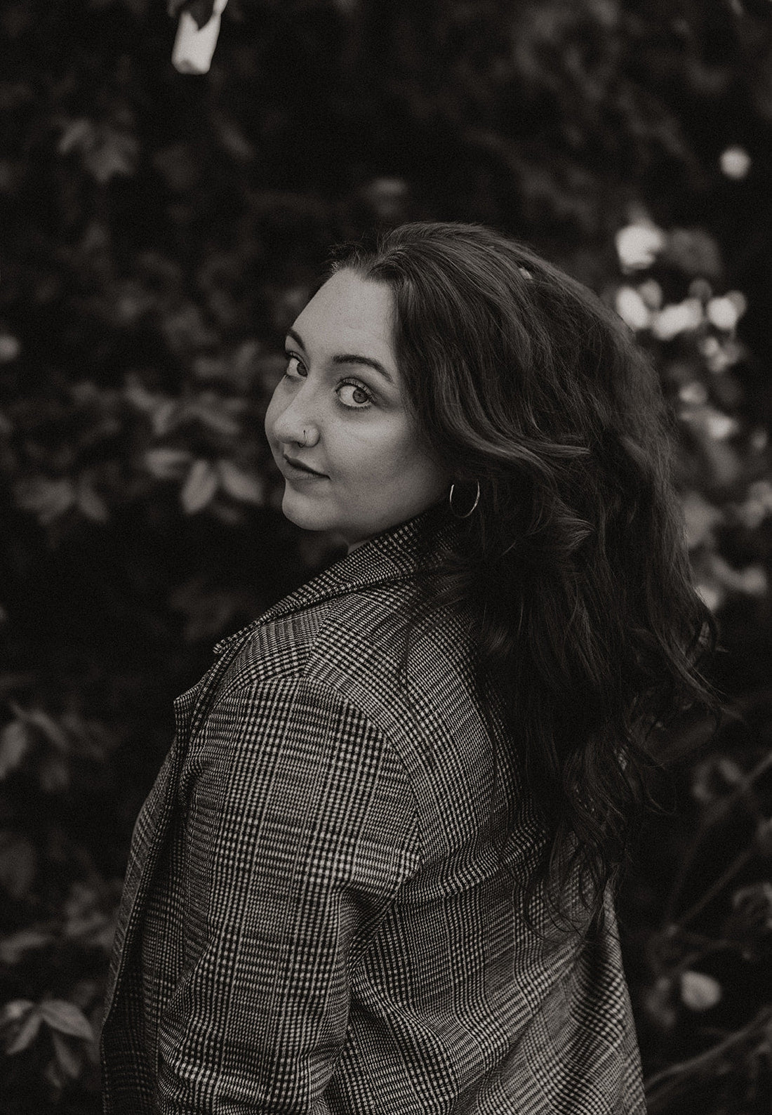 Woman with natural, voluminous waves styled using satin heatless curlers, captured outdoors in a soft black and white portrait.