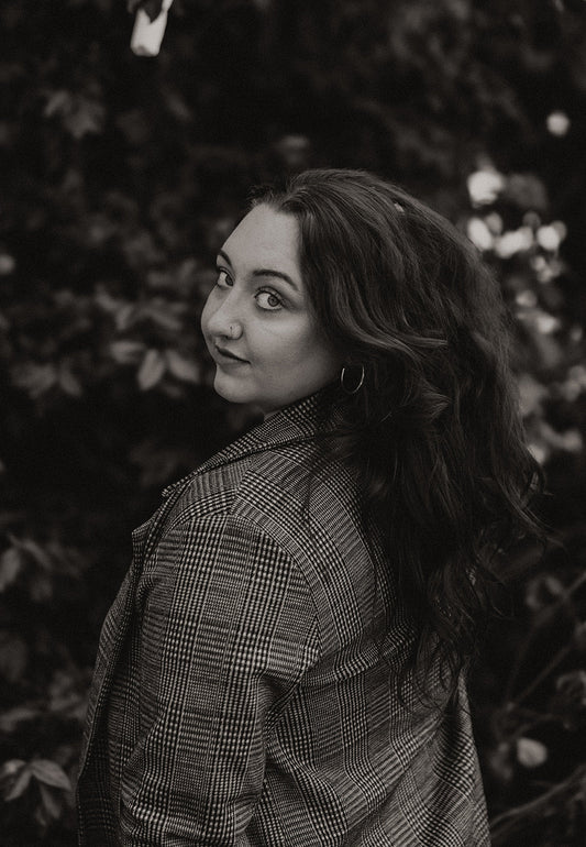 Woman with natural, voluminous waves styled using satin heatless curlers, captured outdoors in a soft black and white portrait.